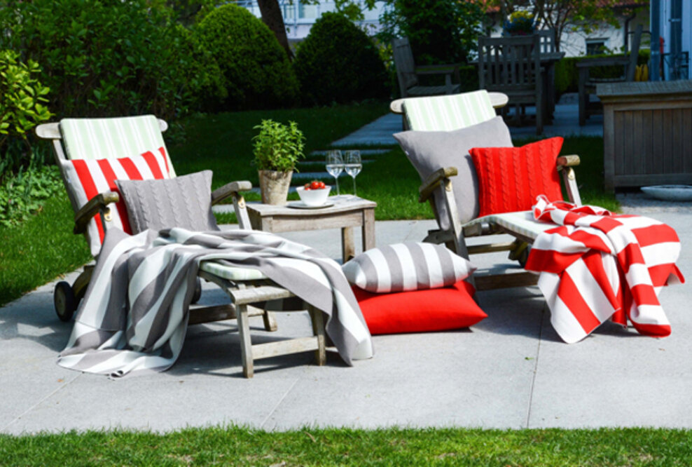Sommerfeeling pur verströmen die edlen Strickdecken und Merinokissen von Lenz & Leif auf Sessel und Sofas