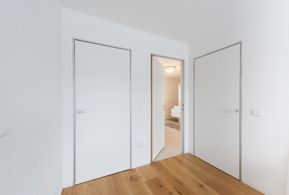 Moderner Minimalismus – wandbündige Türen mit Aluminiumzargen. Schlanke, dezente Zargen passend zum puristischen Architekturstil.