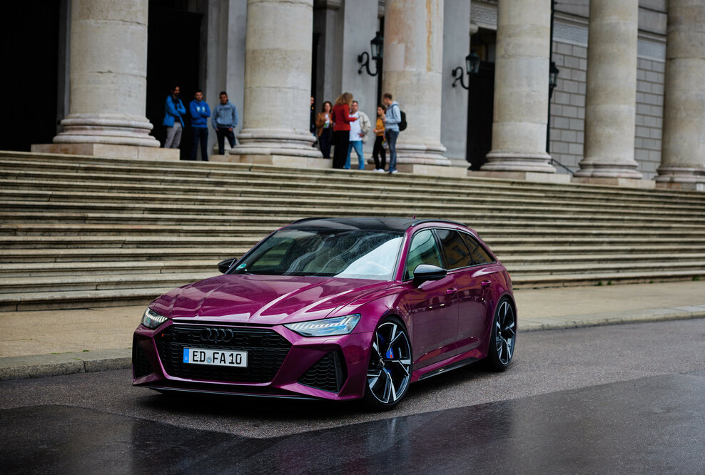20 Jahre Audi RS 6: „Mehr als meinen RS 6 brauche ich nicht!“ - Diesem Auto können sie nicht widerstehen – das zeigen die drei Herren am Ende der Treppe auch durch ihren begeisterten Blick auf den RS 6 Avant in Beere Perleffekt.