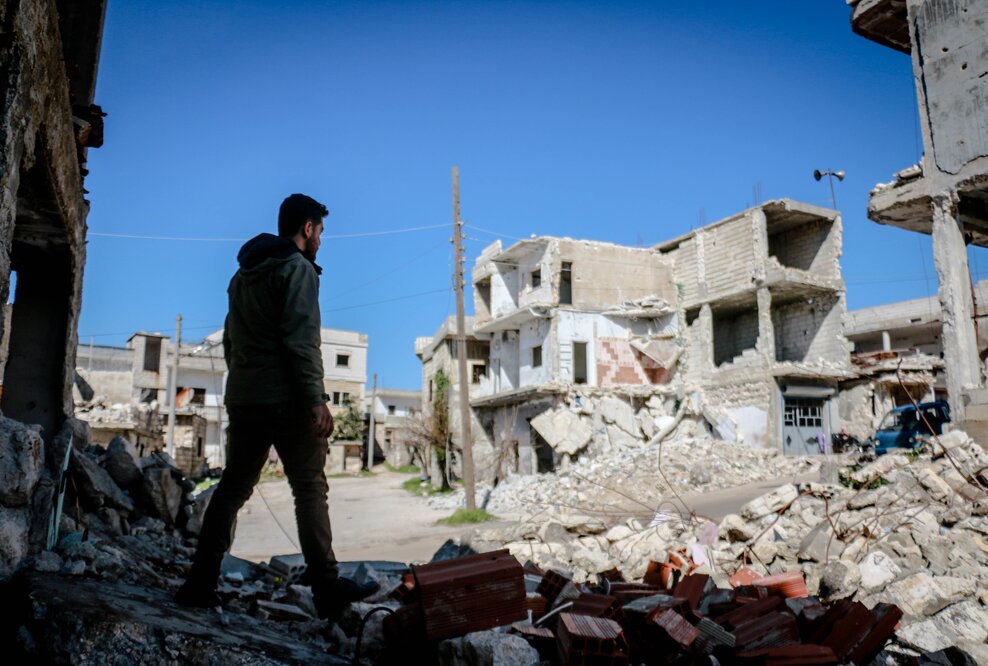 Junger Mann vor einem zerstörten Gebäude