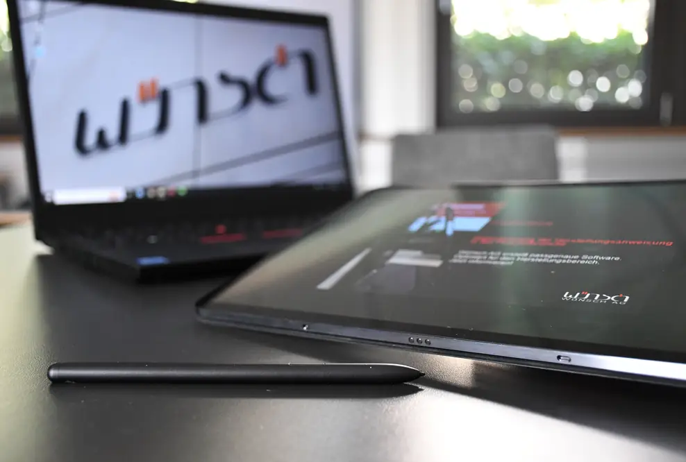 Ein Laptop vor dem ein Tablet liegt.