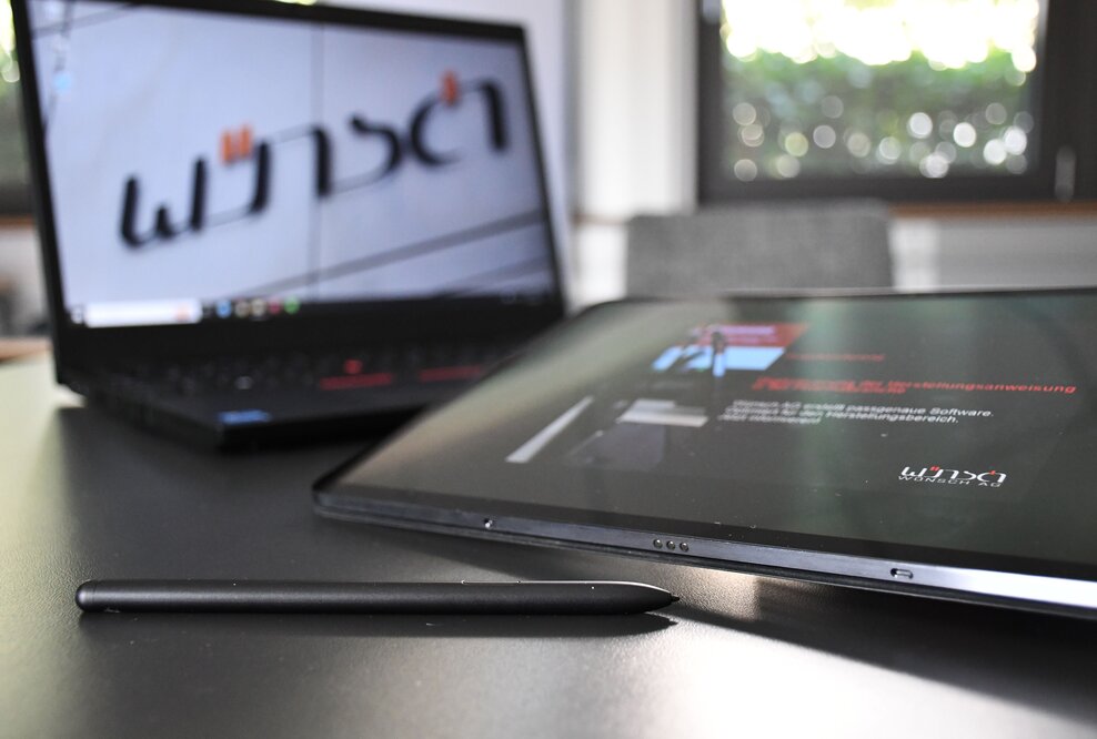 Ein Laptop vor dem ein Tablet liegt.