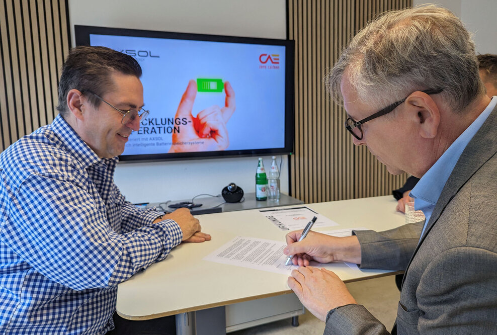 Jürgen Zinecker (AXSOL) und Dr. Hans-Peter Ebert (CAE) unterzeichnen die Entwicklungskooperation. (v. l. n. r.), Bildmaterial AXSOL GmbH 