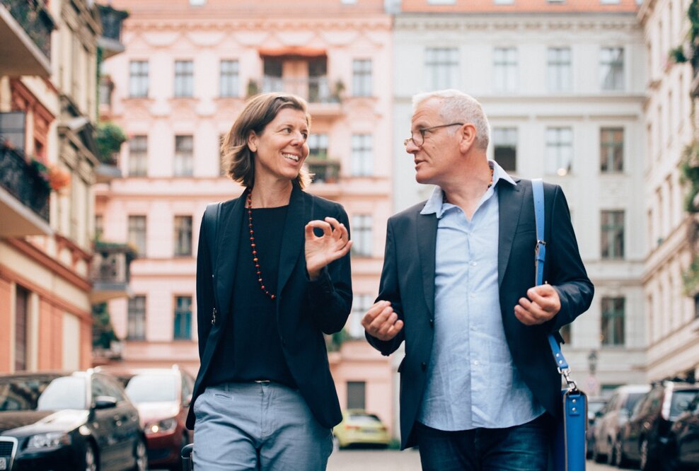 Unternehmerpaar in Unterhaltung über Führungsthemen vertieft, auf dem Weg zu einem Termin