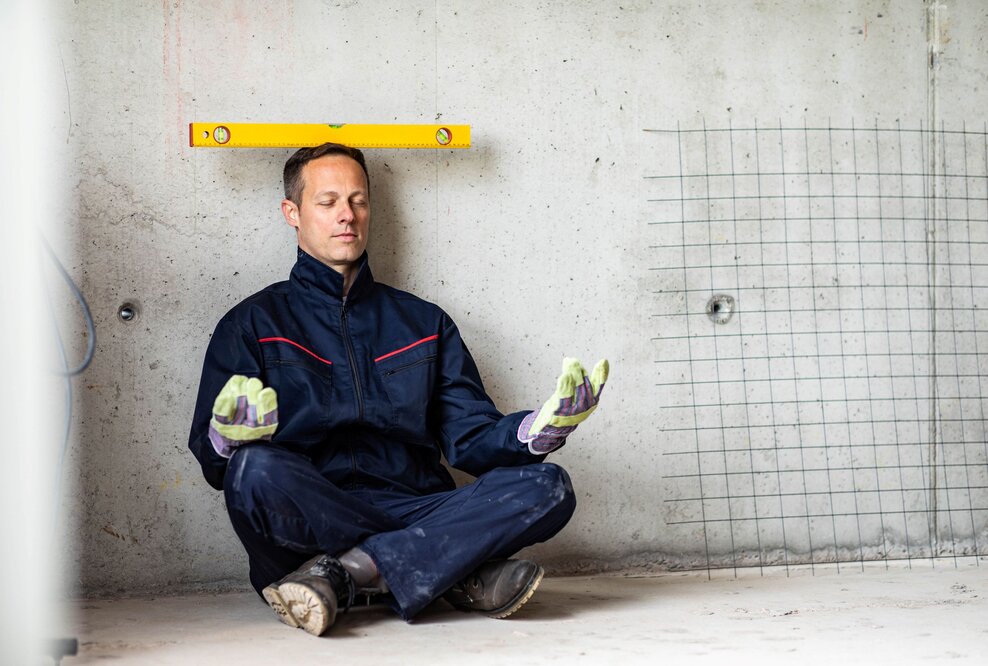 Mann macht ein Art Yogaübung mit Wasserwaage auf dem Kopf