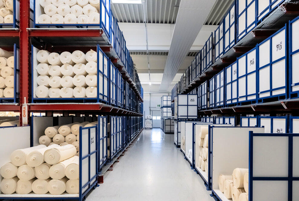 OHRA installierte im Pufferlager von trigema zwischen Herstellung und Ausrüstung Kragarm- und Palettenregale, die eine flexible Zwischenlagerung unterschiedlichster Stoffe ermöglichen. 