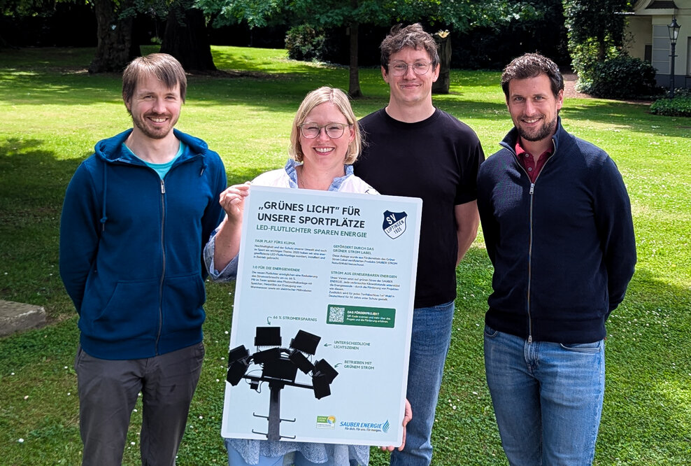 Das Team der SAUBER ENERGIE mit einem Hinweisschild, welches am Spielfeldrand über das Förderprojekt informiert