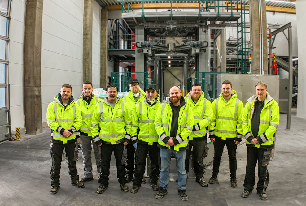 Gruppenbild des Produktionsteams von Dr. Eckel mit der neuen Anlage im Hintergrund