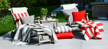 Sommerfeeling pur verströmen die edlen Strickdecken und Merinokissen von Lenz & Leif auf Sessel und Sofas