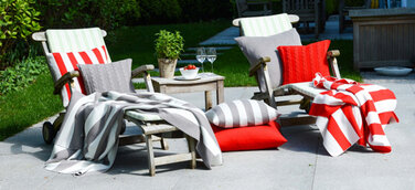 Sommerfeeling pur verströmen die edlen Strickdecken und Merinokissen von Lenz & Leif auf Sessel und Sofas