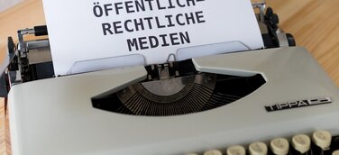 Schreibmaschine mit Papier, auf dem "Öffentlich-Rechtliche Medien" steht.