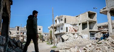 Junger Mann vor einem zerstörten Gebäude