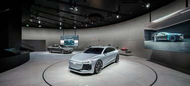 Der Audi A6 e-tron concept und der Plug-in-Hybrid Audi A8 60 TFSI e sowie Exponate auf einem langgestreckten Lowboard erwecken die Themen Digitalisierung und Design zum Leben.