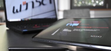 Ein Laptop vor dem ein Tablet liegt.