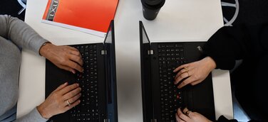 2 Laptops mit tippenden Händen 