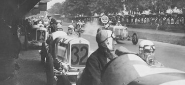 Großer Preis von Deutschland 1926 auf der Berliner AVUS: Die NSU Kompressor-Rennwagen NSU 6/60 PS stehen in den Boxen und warten auf die Freigabe des Starts. Im Wagen Nr. 32 der spätere Sieger in der 1,5-Liter-Klasse Georg Klöble mit Beifahrer Karl Gailing.