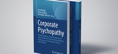 Zwei Bücher mit der Aufschrift "Corporate Psychopathy" stehen auf einem hellgrauen Untergrund und werfen einen Schatten.