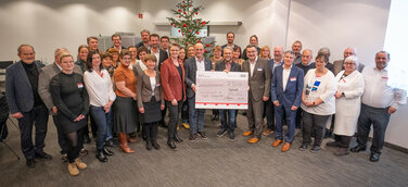 Der Betriebsrat übergibt den symbolischen Spendenscheck der diesjährigen Weihnachtsspende der Audi Belegschaft an die Vertreter_innen sozialer Organisationen aus der Region.