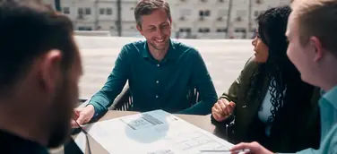 Team Planport bei der Arbeit an einem Tisch, auf dem ein Gebäudeplan liegt