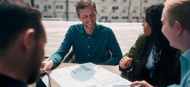 Team Planport bei der Arbeit an einem Tisch, auf dem ein Gebäudeplan liegt
