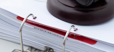 Richterhammer auf einem Aktenordner – Symbol für Bürokratieabbau und neue Regelungen im Vergabetransformationsgesetz.