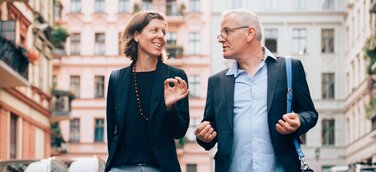 Unternehmerpaar in Unterhaltung über Führungsthemen vertieft, auf dem Weg zu einem Termin