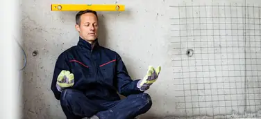 Mann macht ein Art Yogaübung mit Wasserwaage auf dem Kopf