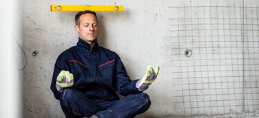 Mann macht ein Art Yogaübung mit Wasserwaage auf dem Kopf