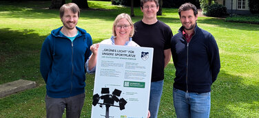 Das Team der SAUBER ENERGIE mit einem Hinweisschild, welches am Spielfeldrand über das Förderprojekt informiert