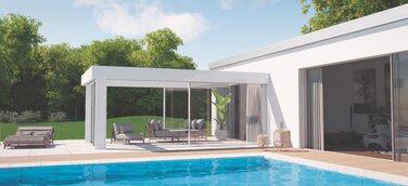 Ein modernes Einfamilienhaus mit klarer, minimalistischer Architektur öffnet sich zu einem großzügigen Garten mit Pool. Im Vordergrund spiegelt sich das strahlend blaue Wasser, während eine elegante Terrassenüberdachung aus Glas und Aluminium den Übergang zwischen Innen und Außen bildet. Stilvolle Loungemöbel, natürliche Farben und harmonisches Licht schaffen eine Atmosphäre von Ruhe, Design und sommerlicher Leichtigkeit.