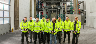 Gruppenbild des Produktionsteams von Dr. Eckel mit der neuen Anlage im Hintergrund