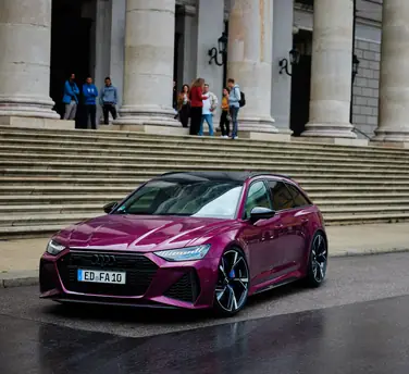 20 Jahre Audi RS 6: „Mehr als meinen RS 6 brauche ich nicht!“ - Diesem Auto können sie nicht widerstehen – das zeigen die drei Herren am Ende der Treppe auch durch ihren begeisterten Blick auf den RS 6 Avant in Beere Perleffekt.