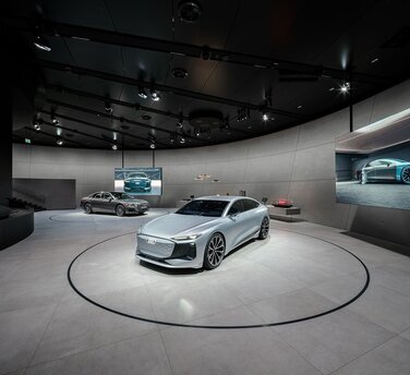 Der Audi A6 e-tron concept und der Plug-in-Hybrid Audi A8 60 TFSI e sowie Exponate auf einem langgestreckten Lowboard erwecken die Themen Digitalisierung und Design zum Leben.