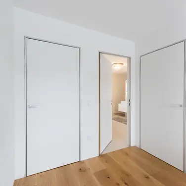 Moderner Minimalismus – wandbündige Türen mit Aluminiumzargen. Schlanke, dezente Zargen passend zum puristischen Architekturstil.
