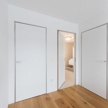 Moderner Minimalismus – wandbündige Türen mit Aluminiumzargen. Schlanke, dezente Zargen passend zum puristischen Architekturstil.