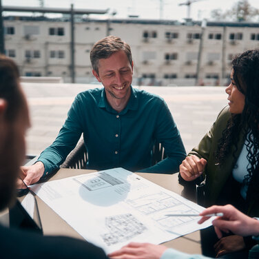 Team Planport bei der Arbeit an einem Tisch, auf dem ein Gebäudeplan liegt