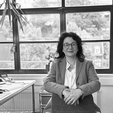 Eine Frau sitzt auf einem Stuhl mit der Stuhllehne nach vorn.