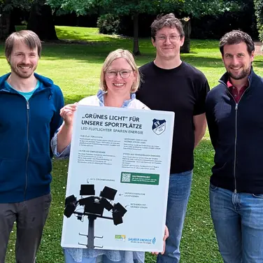 Das Team der SAUBER ENERGIE mit einem Hinweisschild, welches am Spielfeldrand über das Förderprojekt informiert