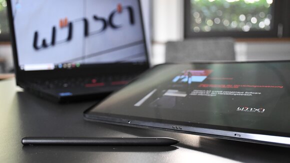 Ein Laptop vor dem ein Tablet liegt.