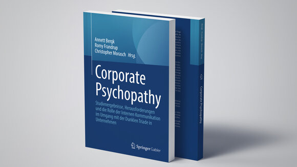 Zwei Bücher mit der Aufschrift "Corporate Psychopathy" stehen auf einem hellgrauen Untergrund und werfen einen Schatten.