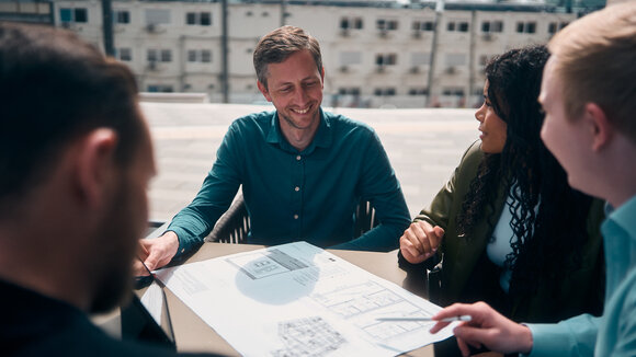 Team Planport bei der Arbeit an einem Tisch, auf dem ein Gebäudeplan liegt