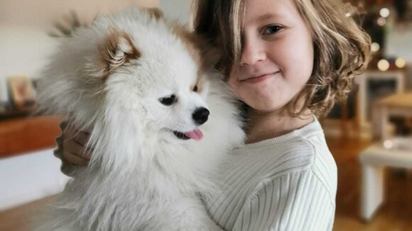 Ein Mädchen, dass einen weißen Hund auf dem Arm hält. 