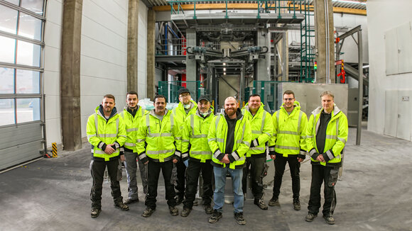 Gruppenbild des Produktionsteams von Dr. Eckel mit der neuen Anlage im Hintergrund