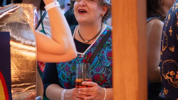 Lächelnde Frau mit einem Glas Aperol in der Hand beim Glöckl auf dem Regensburger Faschingsevent.