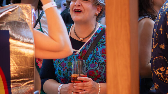 Lächelnde Frau mit einem Glas Aperol in der Hand beim Glöckl auf dem Regensburger Faschingsevent.
